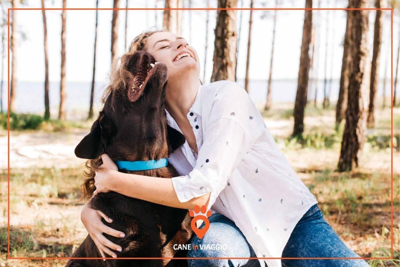 padrona e il suo cane si abbracciano in un bosco